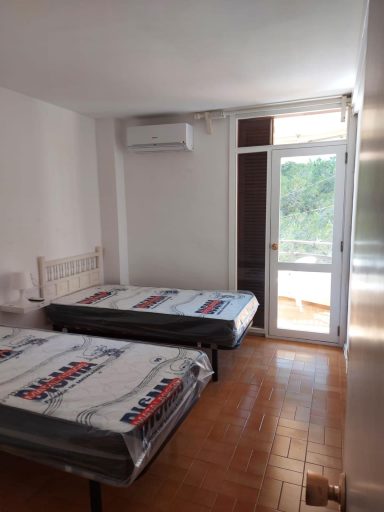 Habitación sencilla con dos camas individuales y ventana que da al exterior.